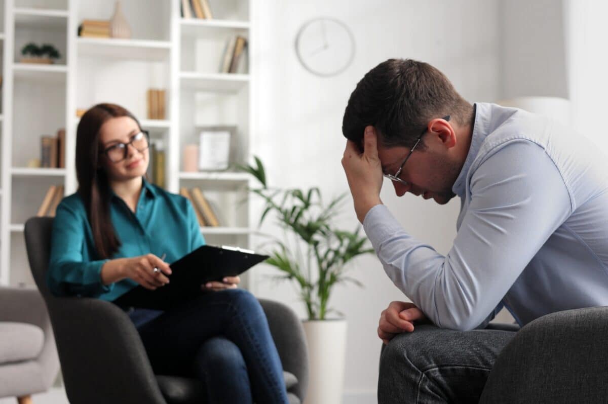 Een professionele psycholoog consulteert een mannelijke patiënt in een staat van stress en depressie
