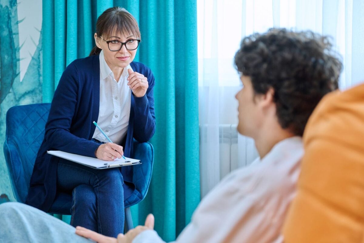 Vrouwelijke psycholoog in gesprek met jonge man, individuele therapiesessie
