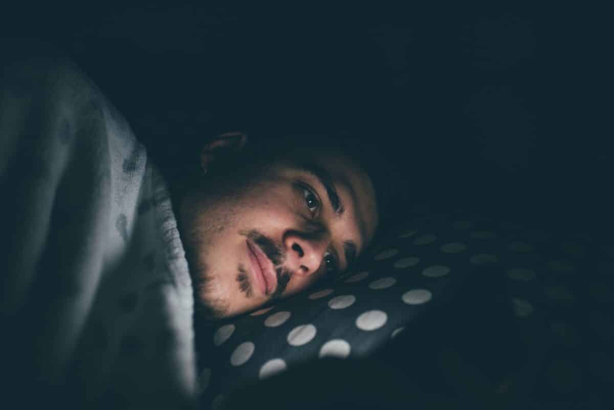 Jonge man binnenshuis in bed 's nachts met smartphone