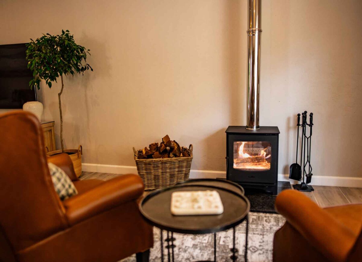 Two cozy armchairs positioned in front of a warm, glowing fireplace, creating a comfortable and inviting atmosphere in a luxurious room at White River Manor