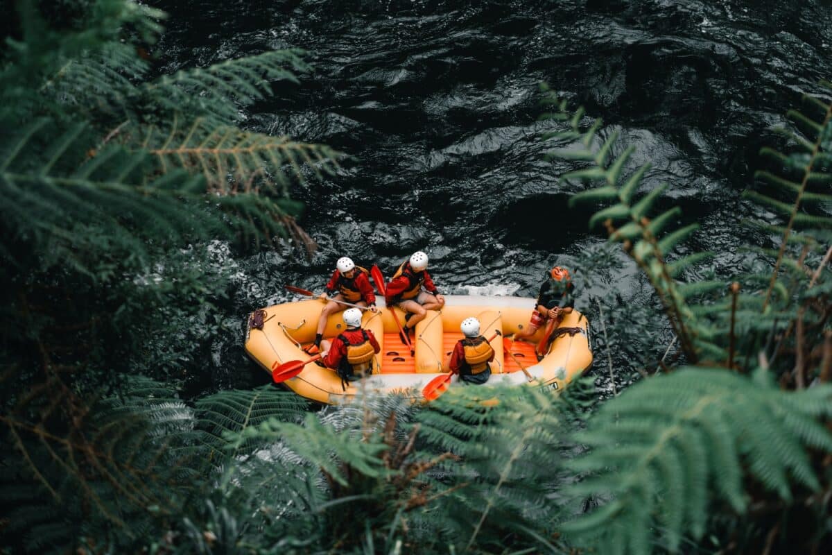 Aerial view of five people wearing swimsuits and life jackets for whitewater rafting