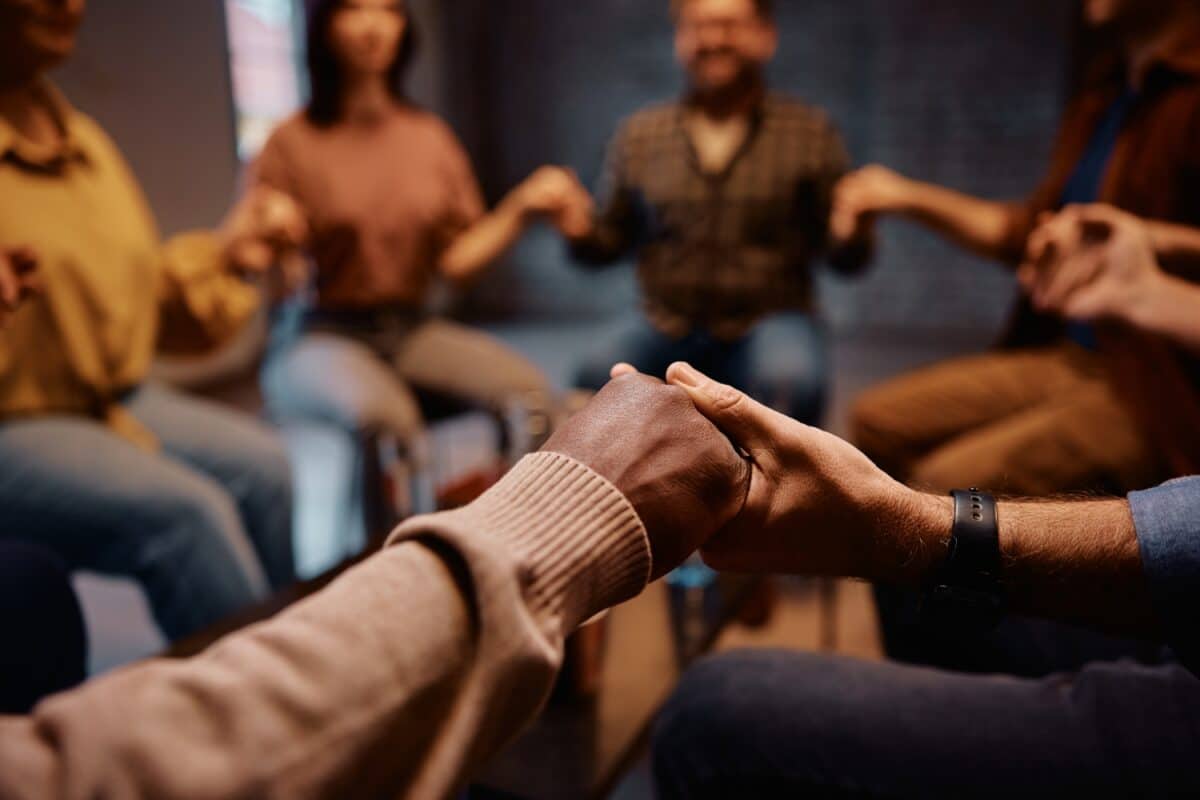 Close up of people holding hands during group therapy at mental health center