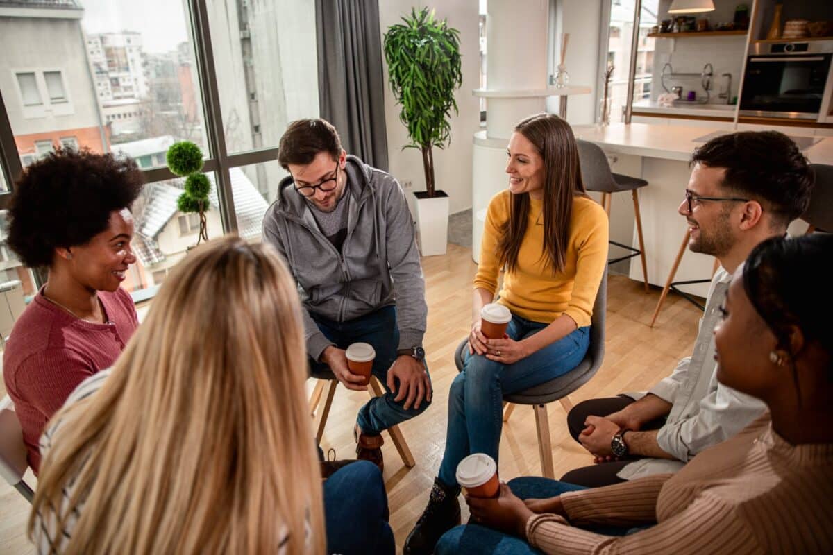 Diverse group of people sitting in circle in group therapy session.