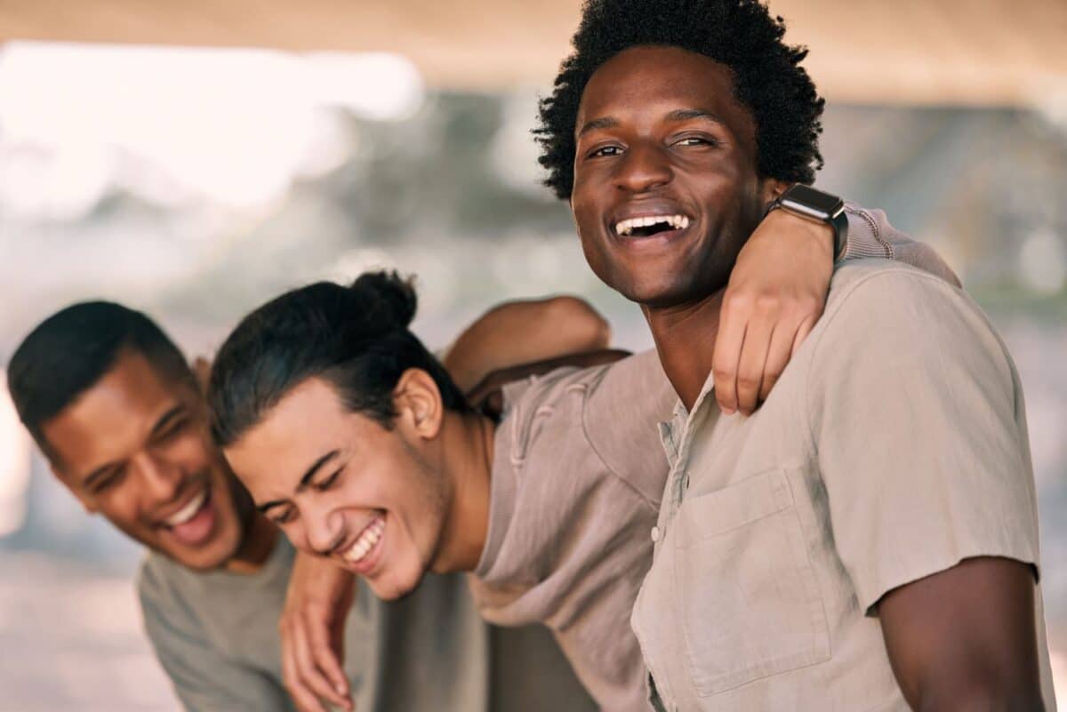 Friends laughing together, men outdoor with hug and funny, relax and happy with diversity