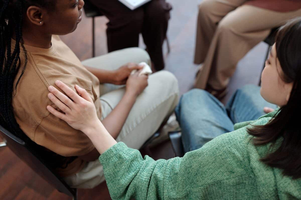 Girl comforting friend during group therapy session