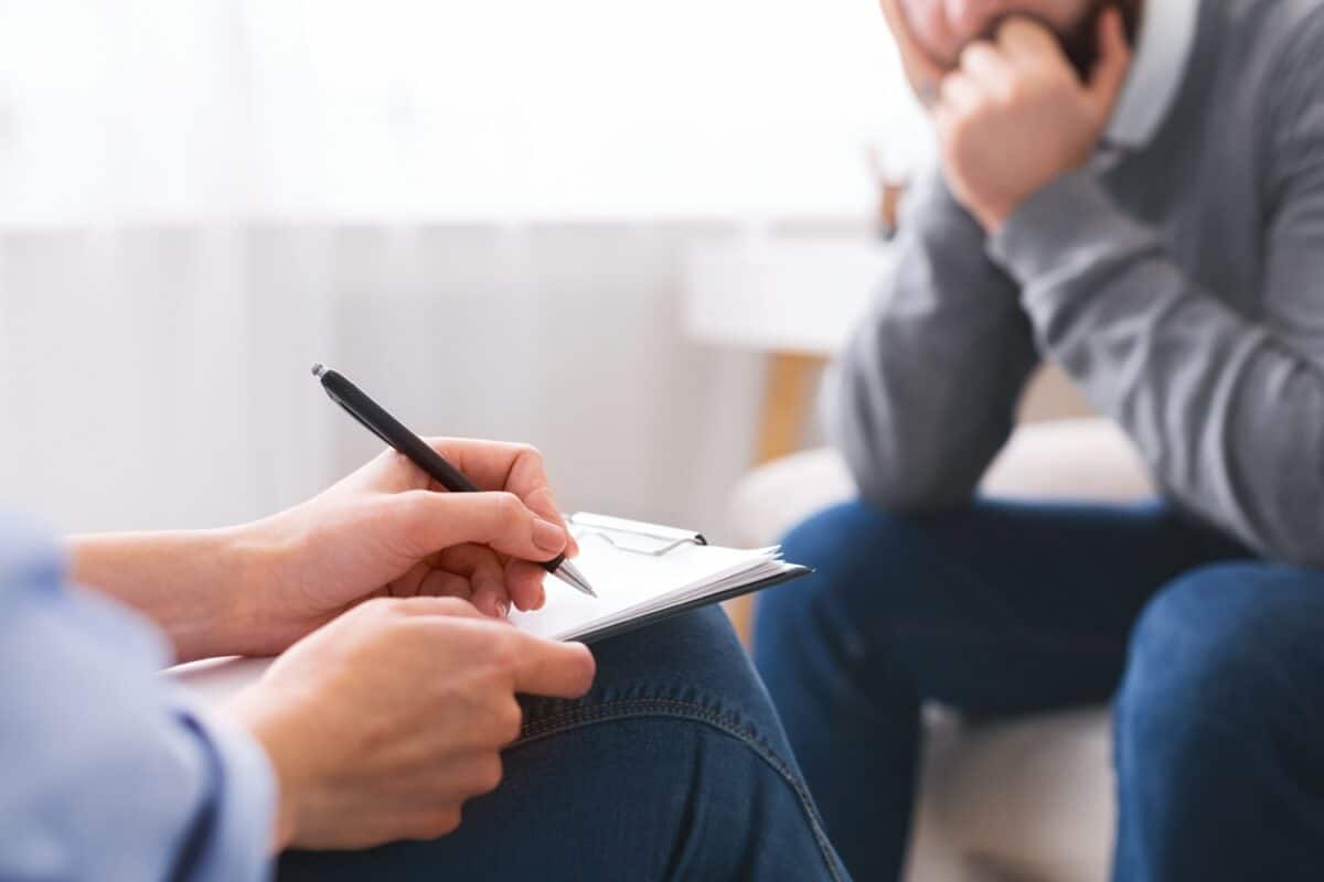 Professional skillful psychologist taking notes, listening to her patient