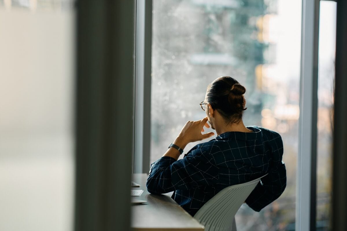 Rear view of businessman looking through the window of his office