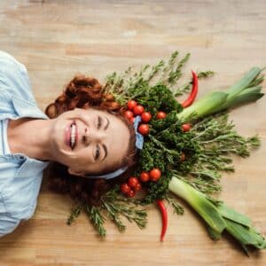 Top view of mature woman in fresh herb and vegetable crown smiling at camera