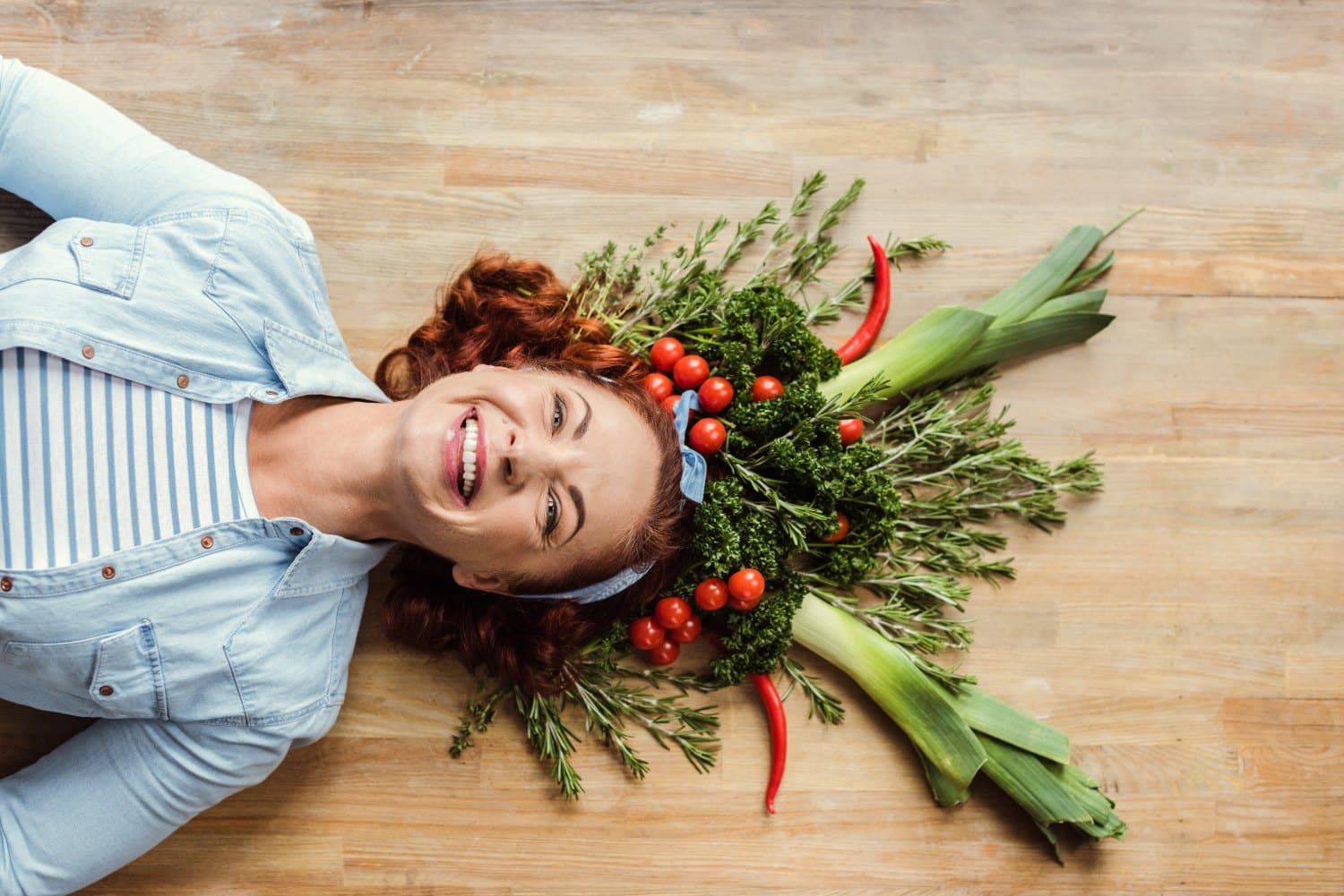 Top view of mature woman in fresh herb and vegetable crown smiling at camera