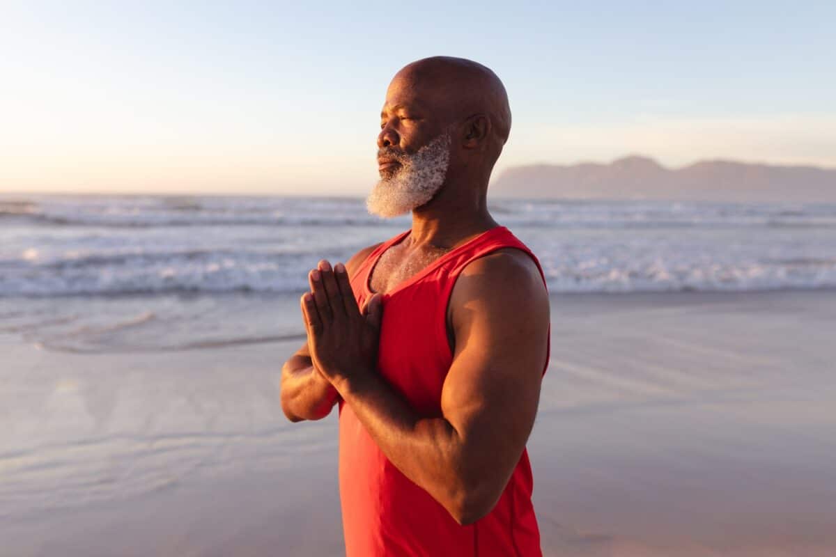 adult black man doing meditation by the beach