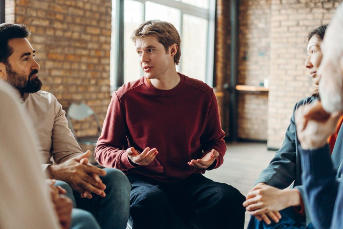 adult man talking to other people while in a group counseling session