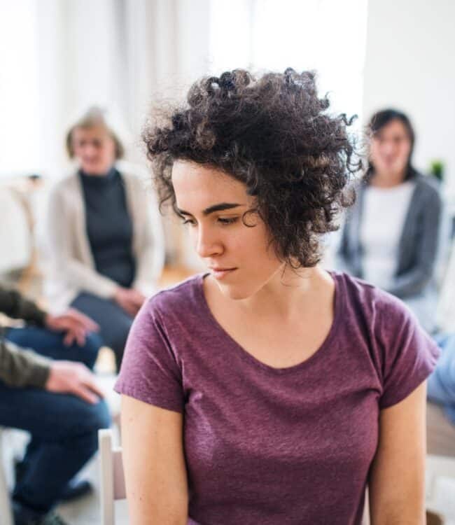 depressed woman thinking deeply with other counseling members behind her, concept of comparison