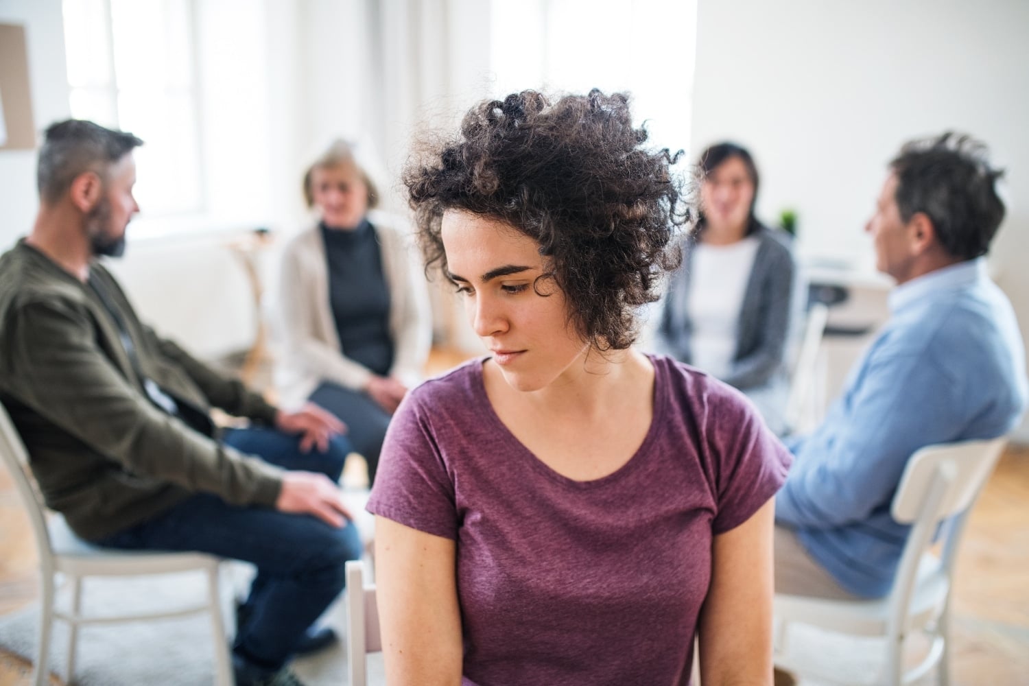 depressed woman thinking deeply with other counseling members behind her, concept of comparison
