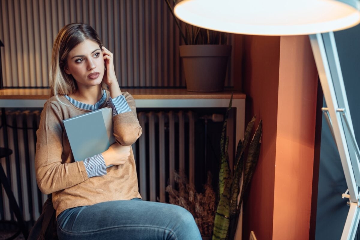 female employee looking anxious while holding office documents, concept of anxiety and burnout