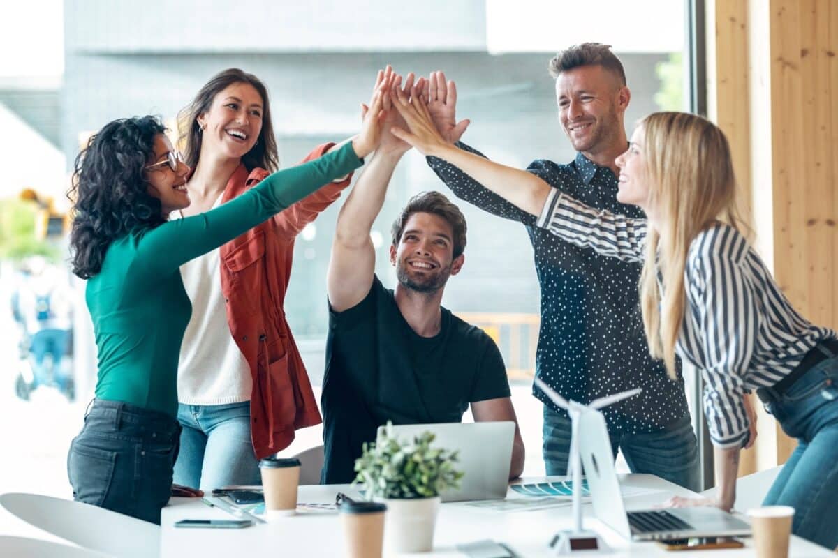 Shot of group of successful smart business team celebrating good job while holding up their right hands on coworking place.