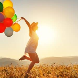 young happy woman with balloons at sunset in summer