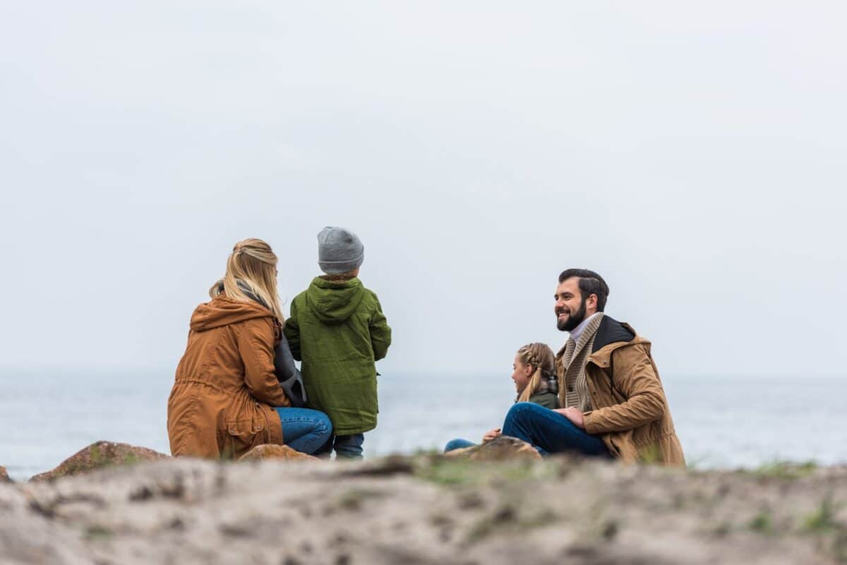 happy young family spending time on seashore on cold autumn day
