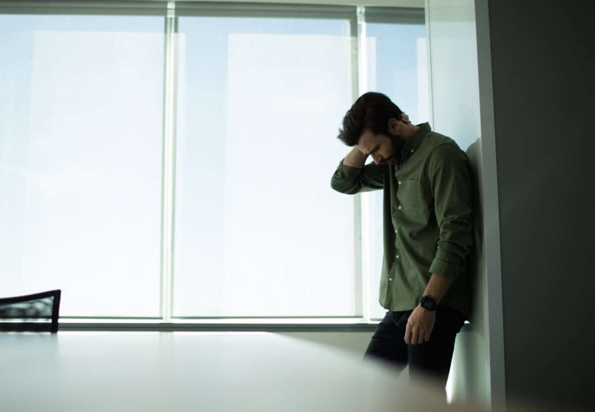 man in an office room, looking depressed, worried
