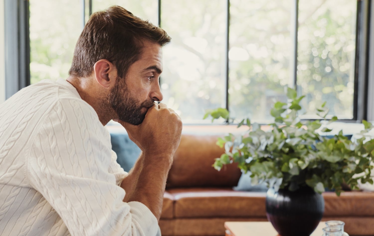 pensive man, sitting alone in the living room looking bored, concept of boredom