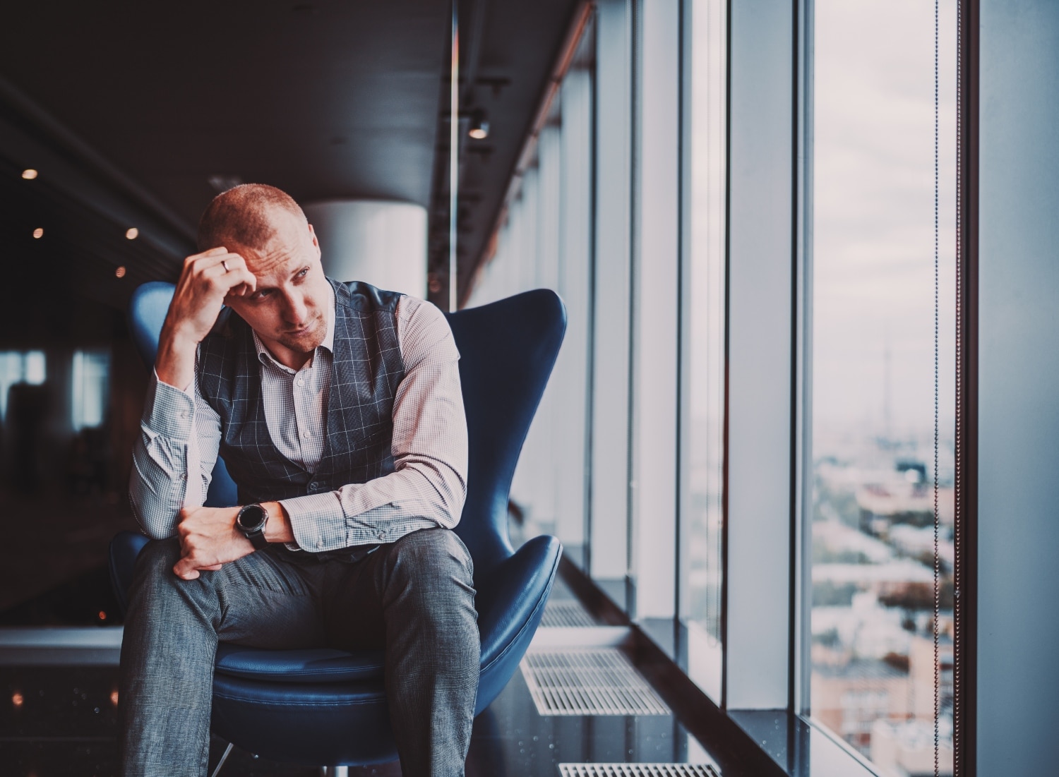pensive man sitting in a chair in an office building, concept of stress and mental health