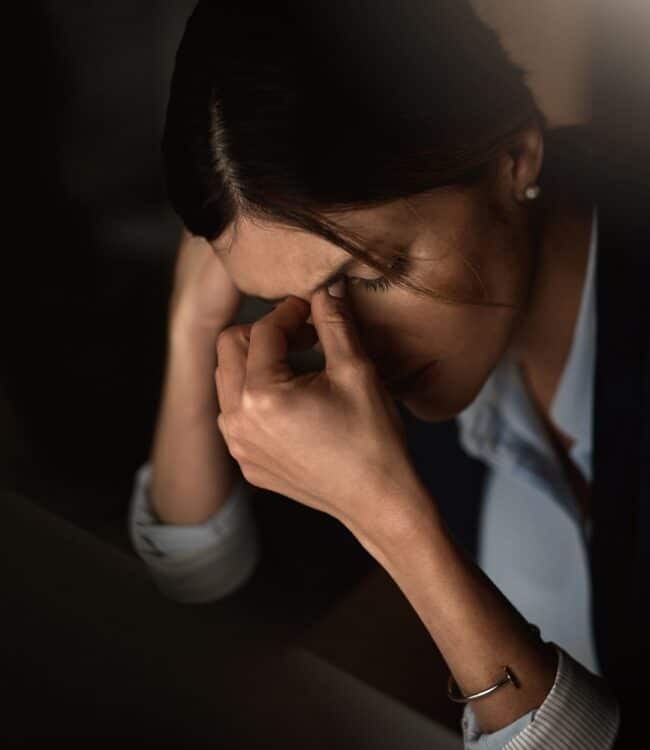 woman with dark hair is experiencing stress, as evidenced by her expression and posture