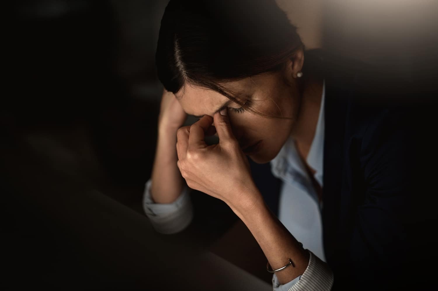 woman with dark hair is experiencing stress, as evidenced by her expression and posture