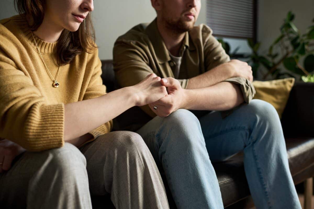 young adult couple sitting while holding hands together during a counseling session