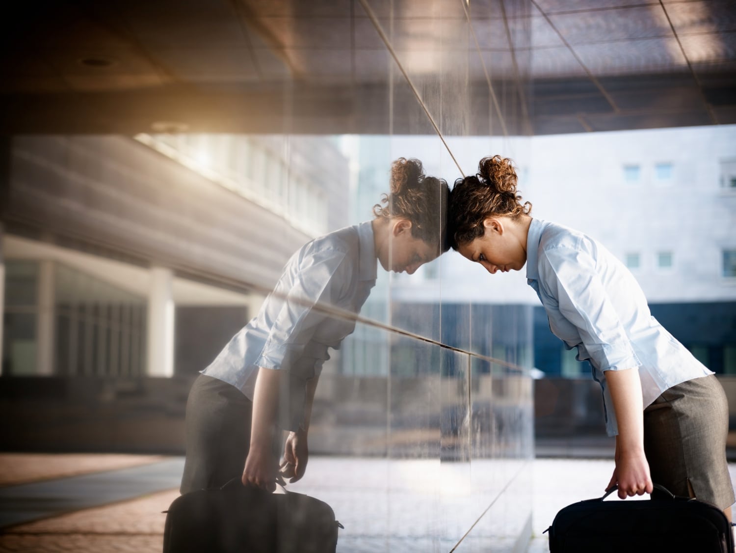 young professional woman leaning head into the wall, sign of stress, anxiety, burnout
