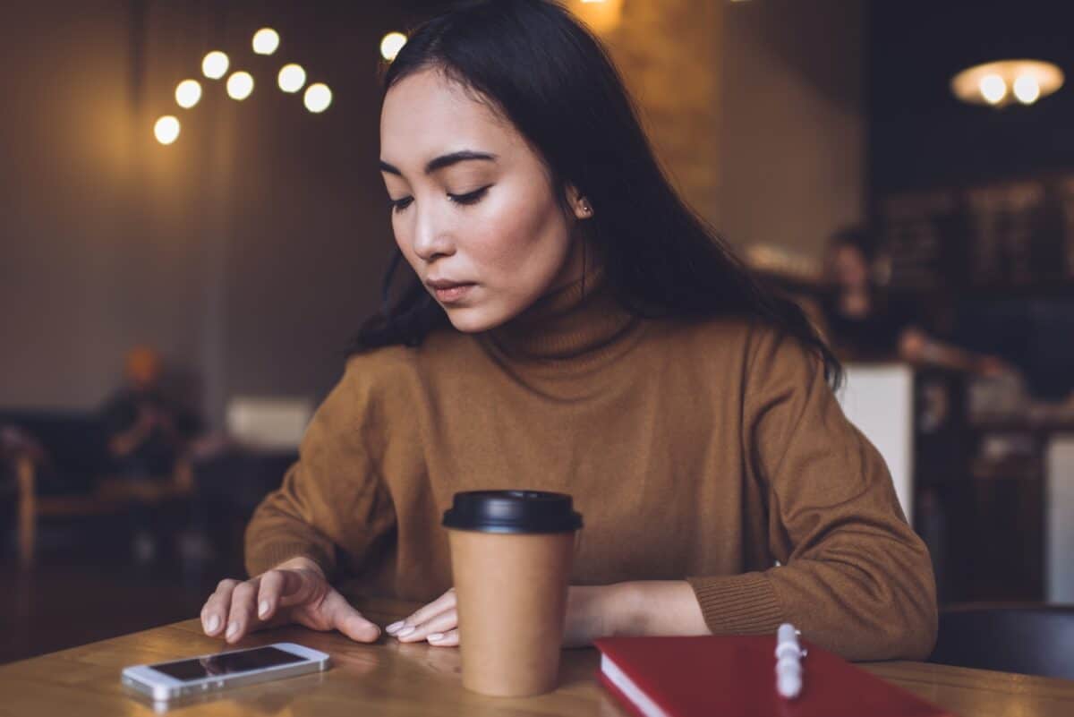 young woman uses mobile phone, looking anxious, worried